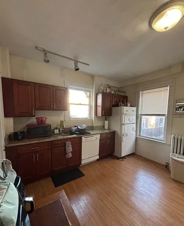 a kitchen with granite countertop a sink cabinets and wooden floor