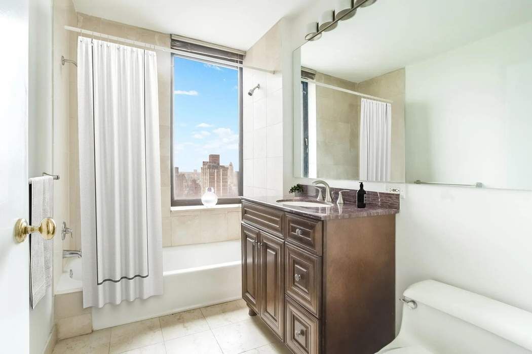 422 East 72nd Street, Unit 33A Manhattan, NY 10021 - Photo 11 of 18 a bathroom with a granite countertop sink a toilet and shower