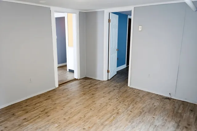 a view of an empty room with wooden floor and closet