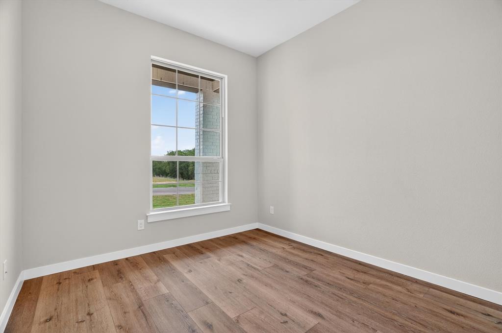 504 Clifton Court Springtown, TX 76082 - Photo 4 of 36 Spacious room featuring wood-finish flooring, light gray wall paint, and white trim