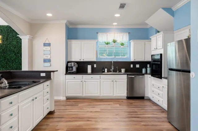 a kitchen with stainless steel appliances a refrigerator sink and white cabinets