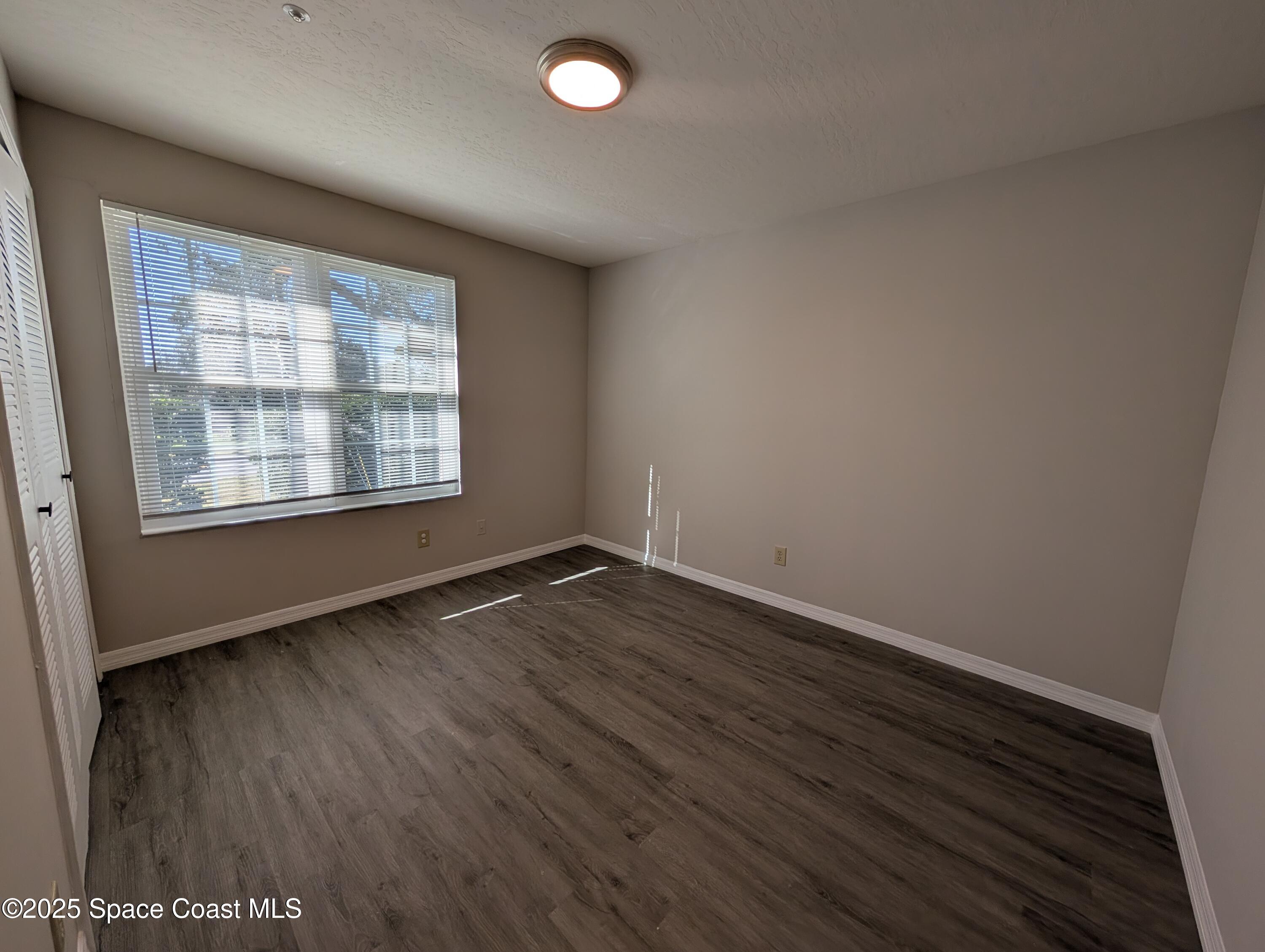 7667 North Wickham Road, Unit 1209 Melbourne, FL 32940 - Photo 12 of 23 an empty room with wooden floor and windows