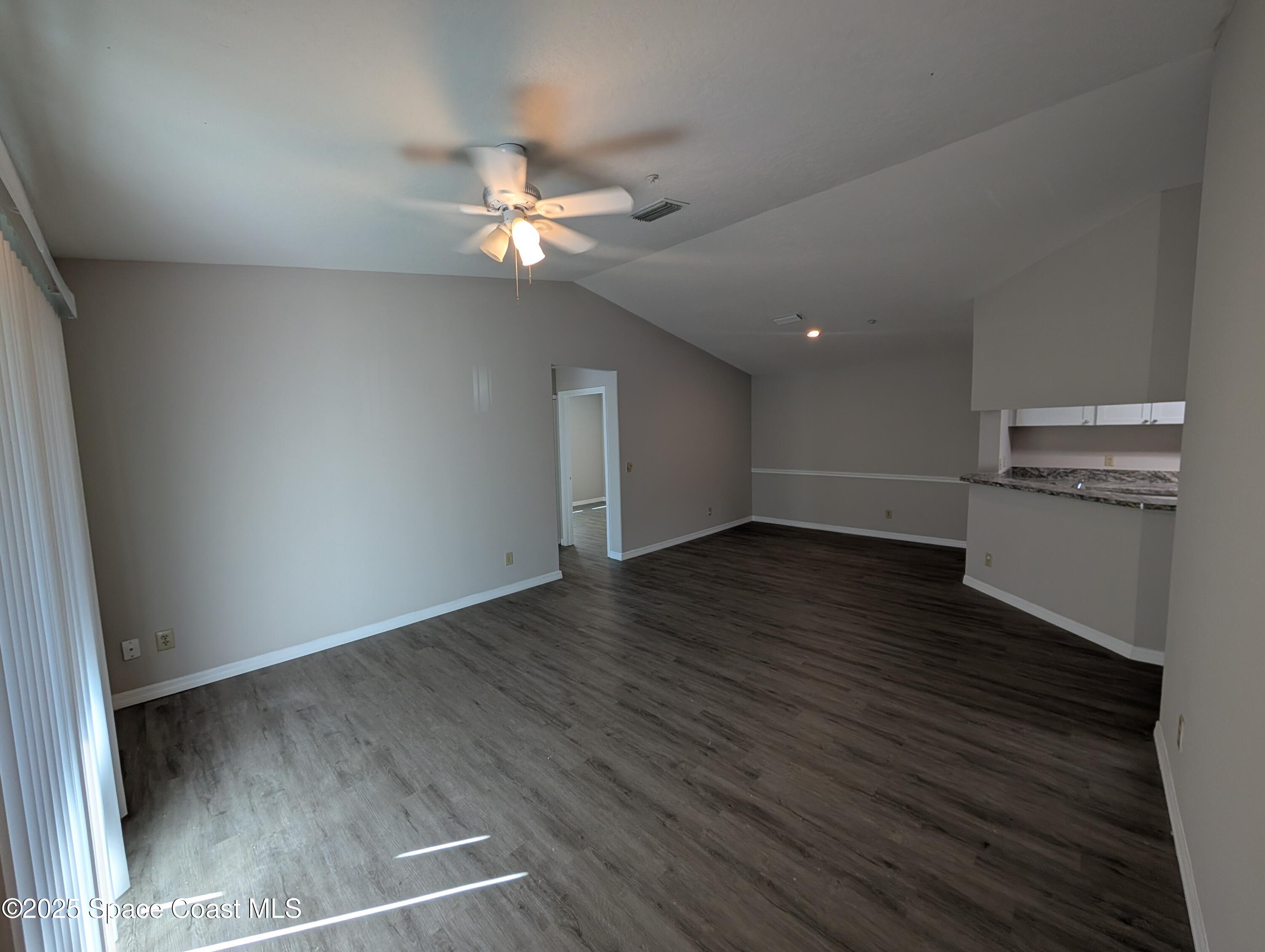 7667 North Wickham Road, Unit 1209 Melbourne, FL 32940 - Photo 3 of 23 an empty room with wooden floor fan and windows