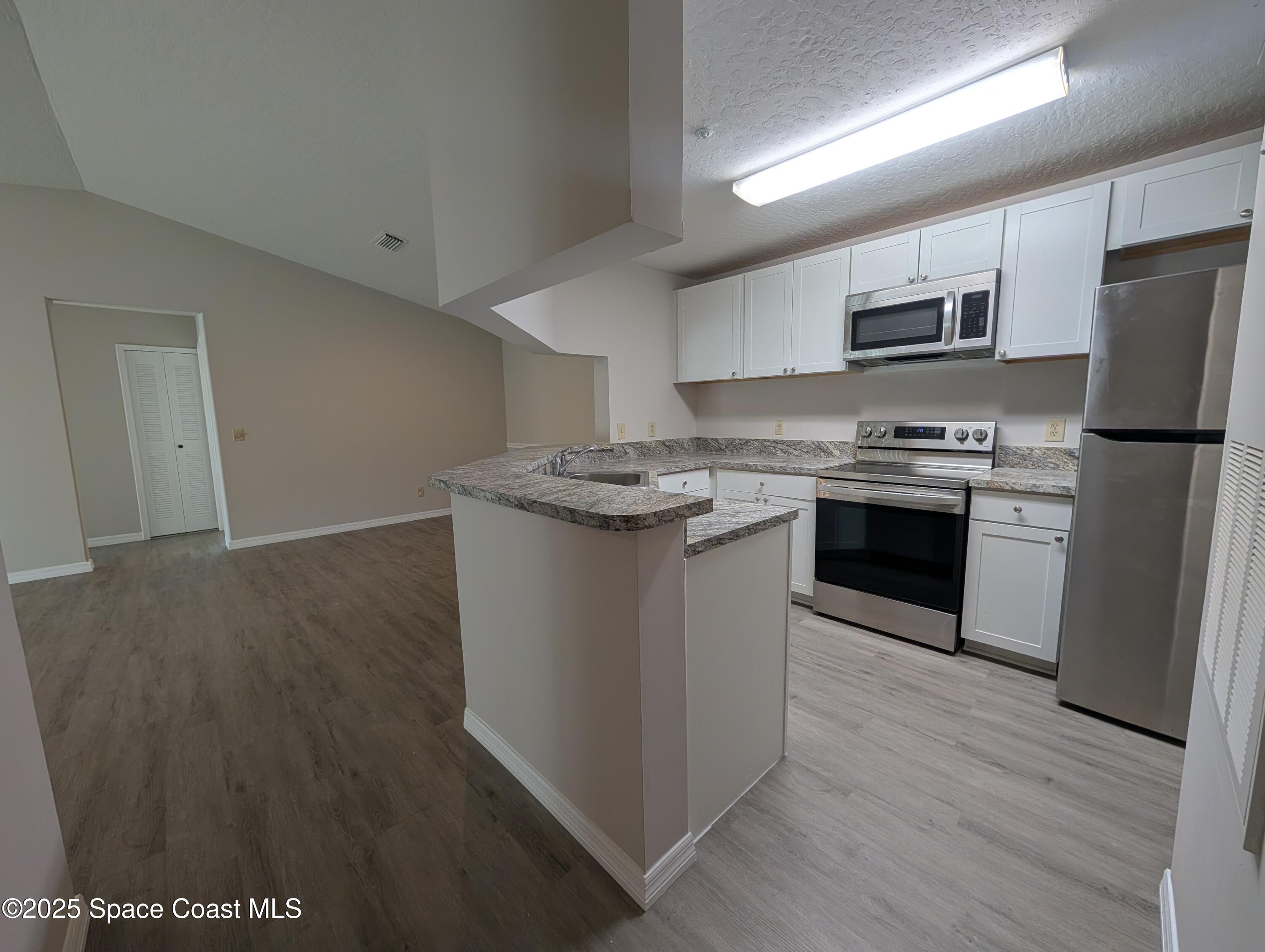 7667 North Wickham Road, Unit 1209 Melbourne, FL 32940 - Photo 5 of 23 a kitchen with stainless steel appliances granite countertop a stove a sink dishwasher a refrigerator and a stove