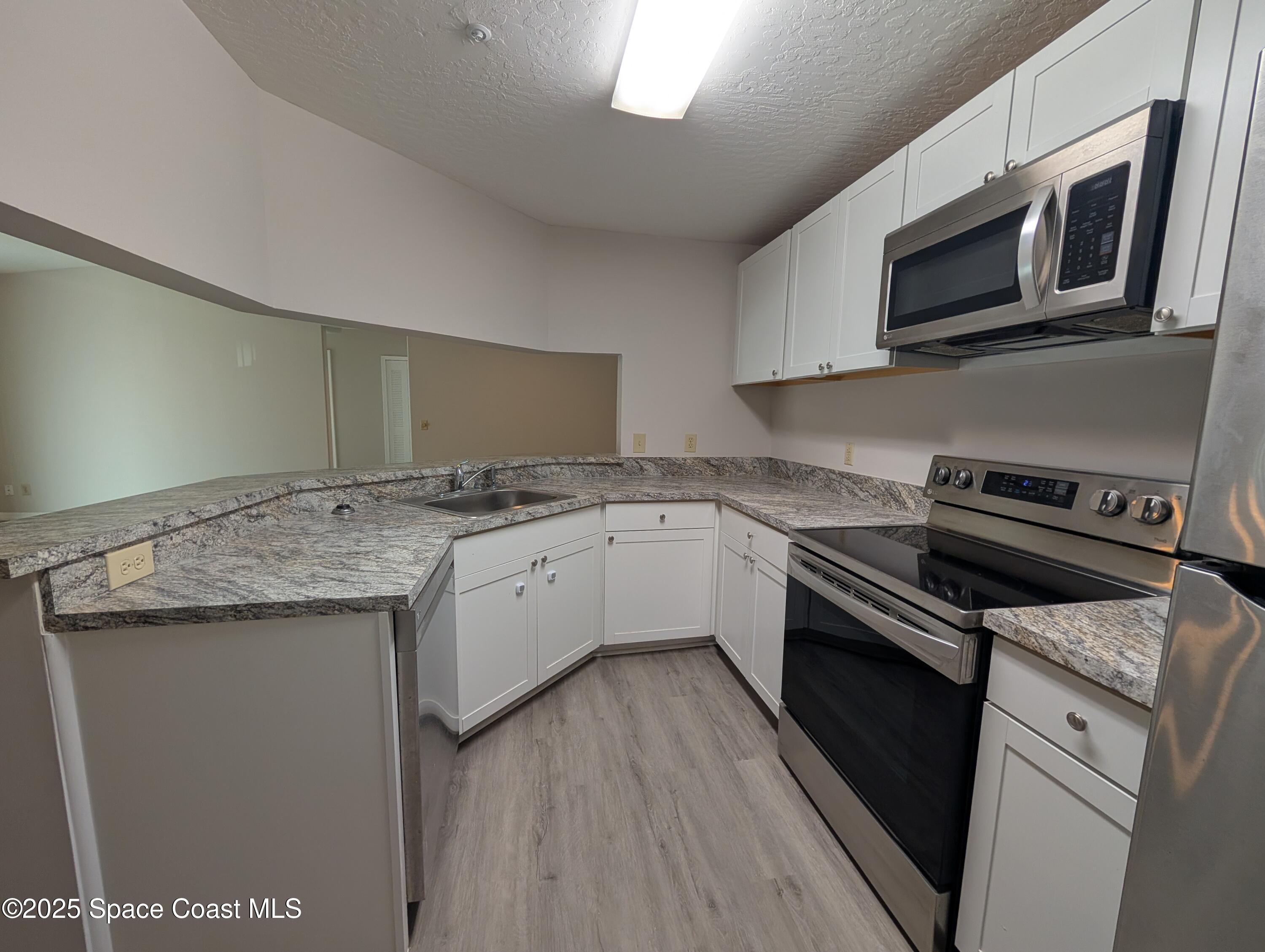 7667 North Wickham Road, Unit 1209 Melbourne, FL 32940 - Photo 6 of 23 a kitchen with granite countertop cabinets stainless steel appliances and a sink