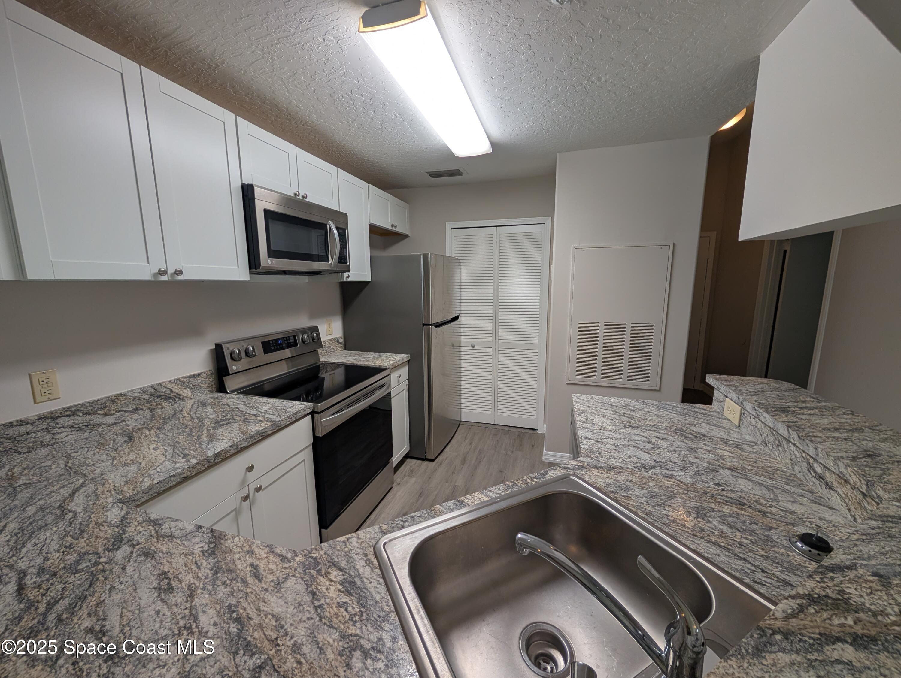 7667 North Wickham Road, Unit 1209 Melbourne, FL 32940 - Photo 7 of 23 a kitchen with stainless steel appliances granite countertop a sink stove and refrigerator