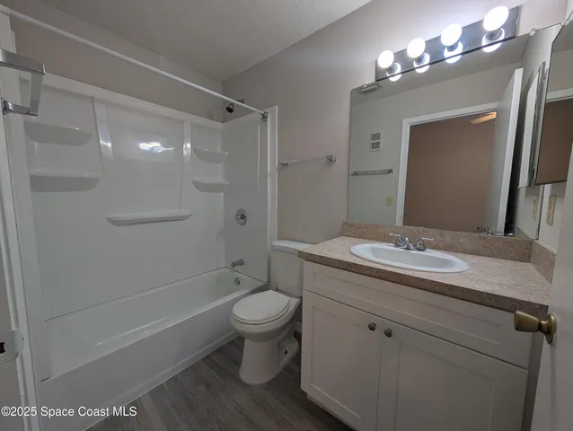 a bathroom with a granite countertop sink toilet a large mirror a shower and bathtub