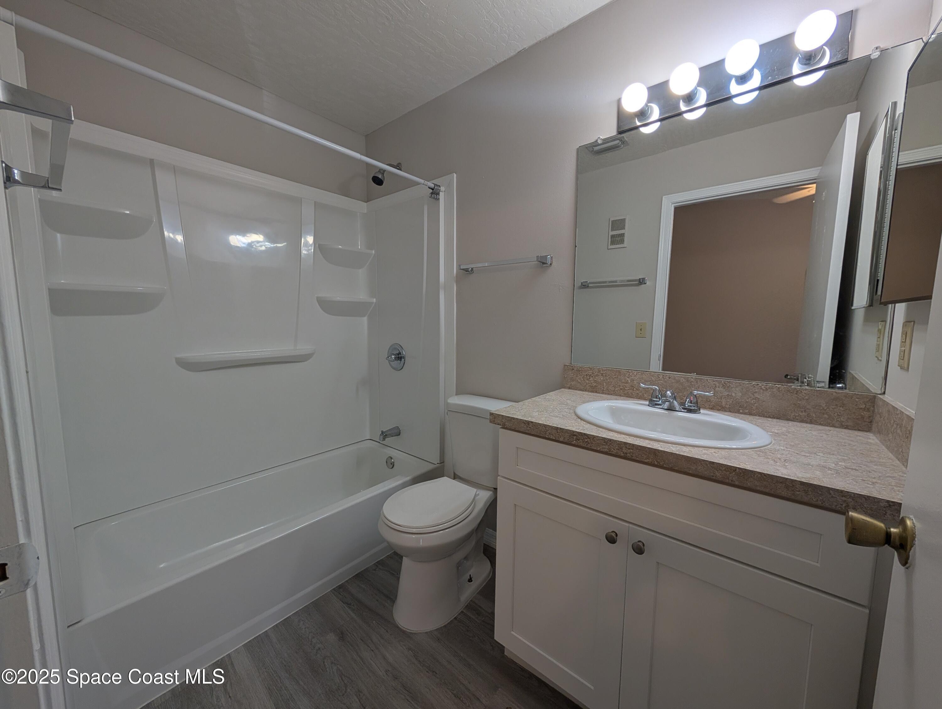 7667 North Wickham Road, Unit 1209 Melbourne, FL 32940 - Photo 10 of 23 a bathroom with a granite countertop sink toilet a large mirror a shower and bathtub
