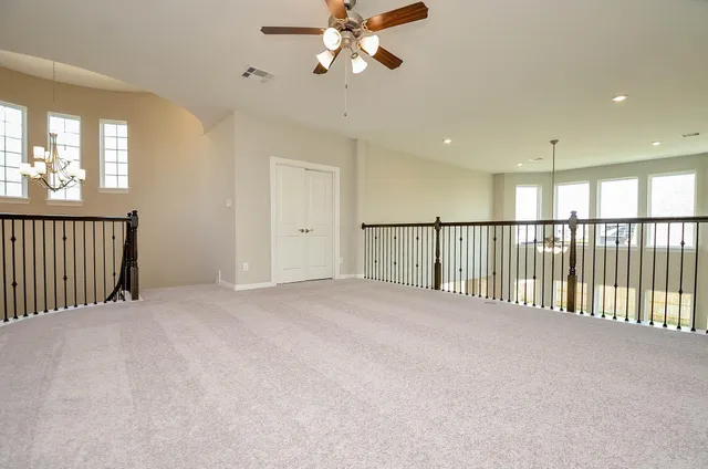 a view of a hallway with a ceiling fan and windows