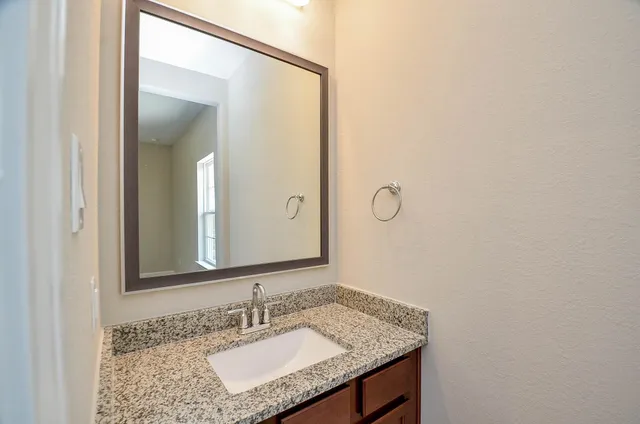 a bathroom with a granite countertop sink and a mirror