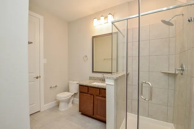 a bathroom with a granite countertop sink a toilet and shower