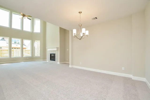 a view of an empty room with a chandelier fan and a window