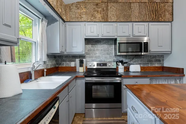 a kitchen with stainless steel appliances granite countertop a stove a sink and a microwave