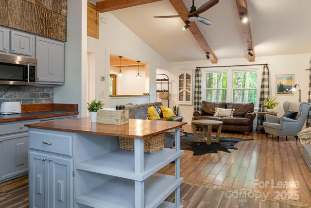 a living room with furniture a large window with stainless steel appliances
