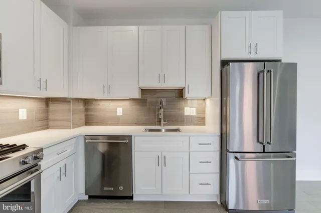 a kitchen with stainless steel appliances granite countertop a refrigerator sink and white cabinets