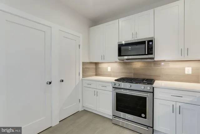 a kitchen with cabinets stainless steel appliances and wooden floor