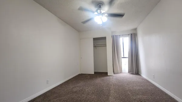 an empty room with a chandelier fan and windows