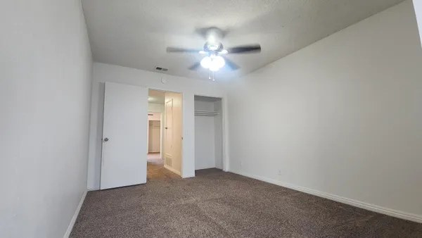 a view of an empty room and a ceiling fan window