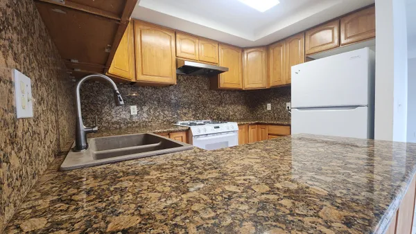 a kitchen with granite countertop a refrigerator and a stove top oven