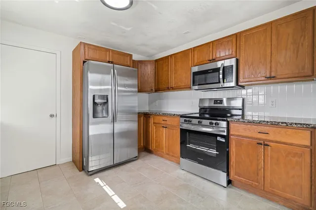 a kitchen with stainless steel appliances granite countertop a refrigerator stove and sink