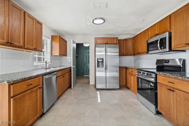 a kitchen with stainless steel appliances granite countertop a stove a sink dishwasher a refrigerator and a microwave oven
