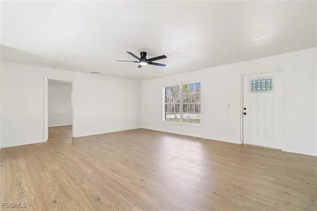 a view of an empty room with a window and wooden floor