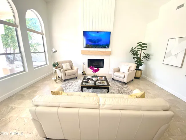a living room with furniture a fireplace and potted plants