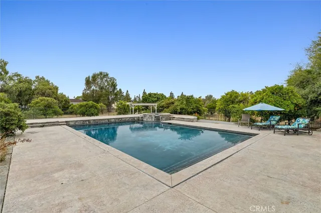 a view of a swimming pool with lawn chairs under an umbrella
