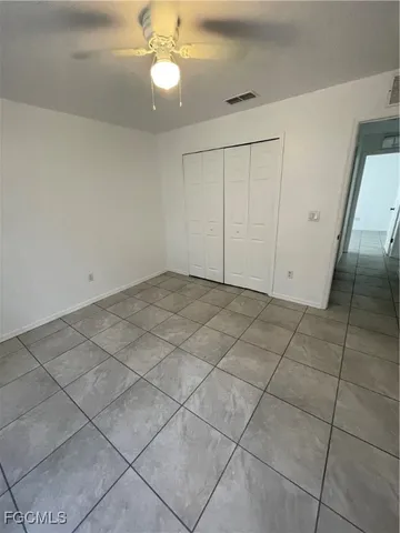 a view of an empty room and chandelier fan