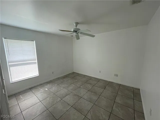 an empty room with a ceiling fan and window