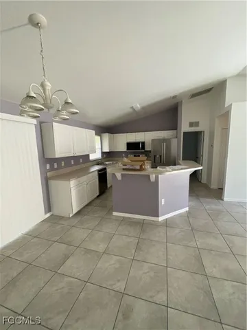 a kitchen with stainless steel appliances a sink a stove a refrigerator cabinets and living room view
