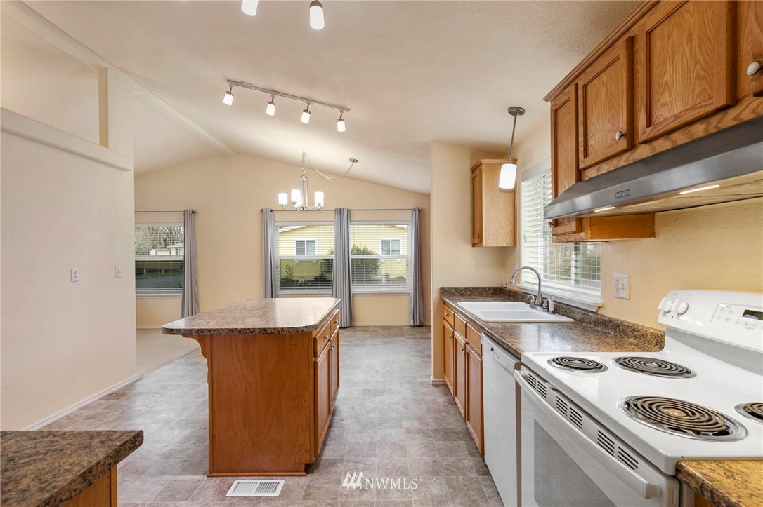 3532 Sylvan Pines Circle Bremerton, WA 98310 - Photo 12 of 22 a kitchen with kitchen island a stove a sink and a refrigerator