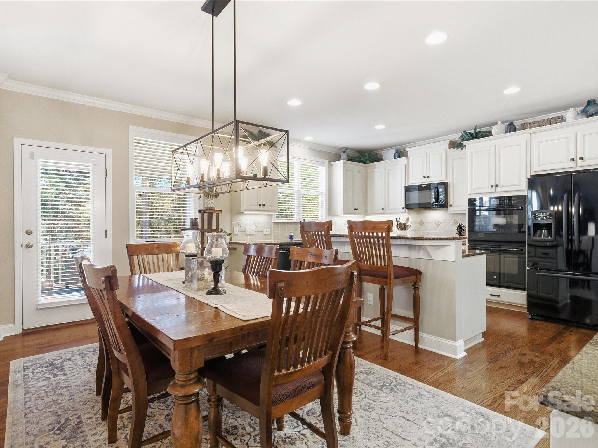 6318 Riverside Oaks Drive Huntersville, NC 28078 - Photo 15 of 48 a dining room with stainless steel appliances kitchen island granite countertop a dining table chairs and a white refrigerator