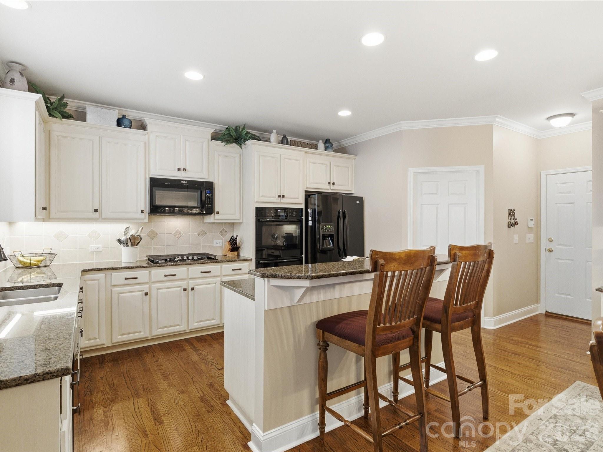 6318 Riverside Oaks Drive Huntersville, NC 28078 - Photo 22 of 48 a kitchen with stainless steel appliances kitchen island granite countertop a stove a sink a refrigerator and white cabinets with wooden floor
