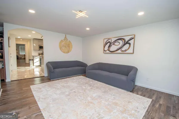 a living room with couches and kitchen view with wooden floor