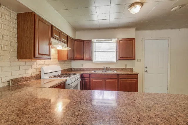a large kitchen with granite countertop a stove a sink dishwasher and a microwave oven on the blue kitchen countertops