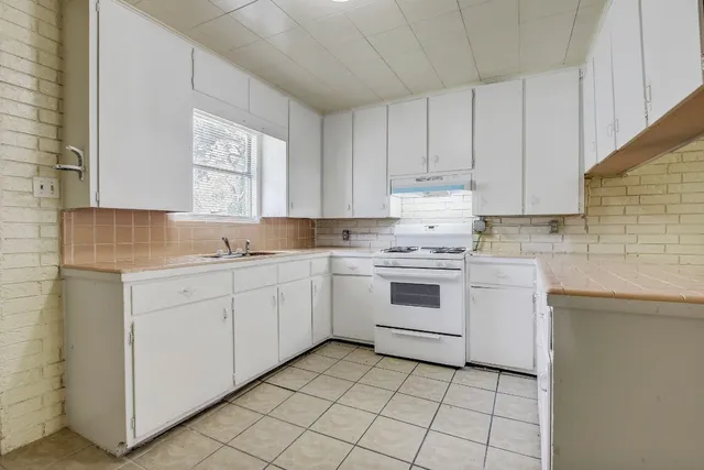 a kitchen with cabinets appliances a sink and a window
