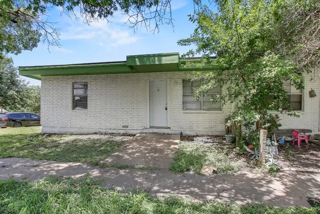 a view of a house with a yard and large tree