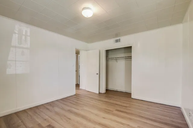 a view of an empty room with wooden floor and closet