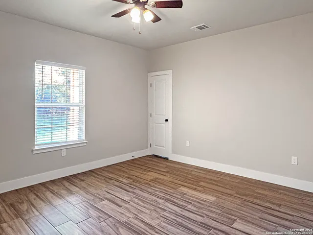an empty room with wooden floor and windows