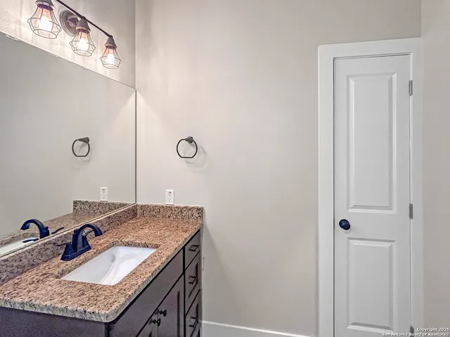 a bathroom with a granite countertop sink and a mirror