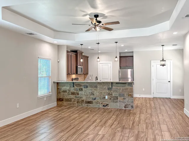 a room with a chandelier fan and wooden floor