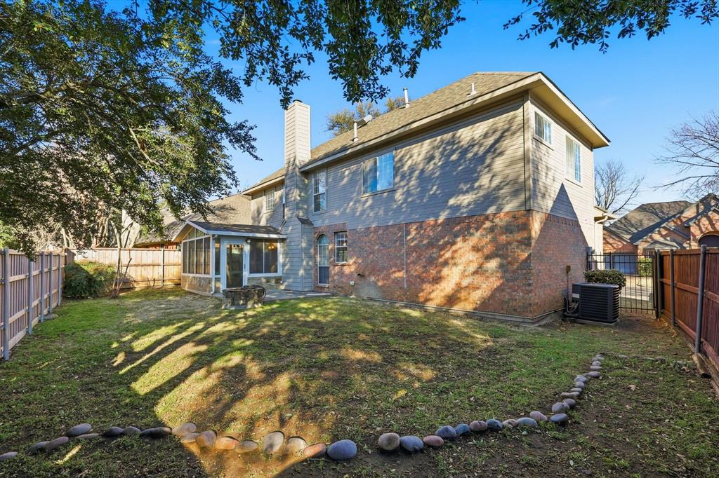 5023 Falcon Hollow Road McKinney, TX 75072 - Photo 23 of 25 Back of property featuring brick siding, a fenced backyard, a sunroom, and a chimney