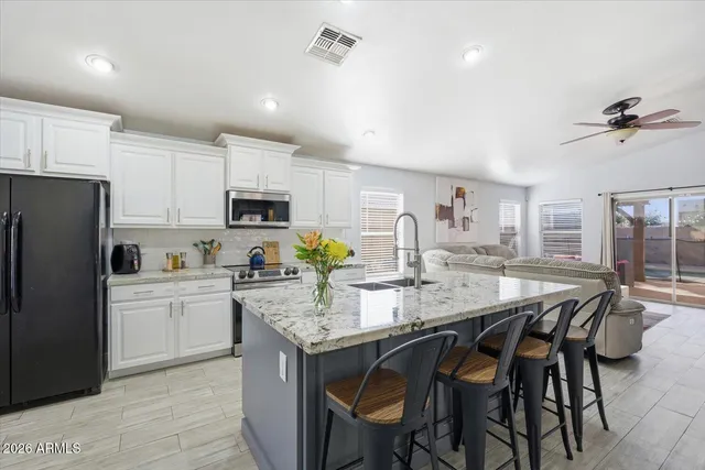 a kitchen with stainless steel appliances granite countertop a stove a refrigerator a sink a dining table and chairs
