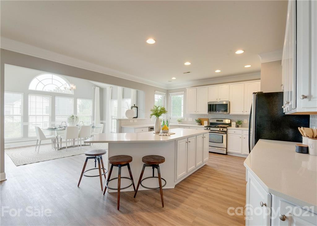2314 Mermans Road Charlotte, NC 28270 - Photo 10 of 45 a kitchen with stainless steel appliances kitchen island granite countertop a stove a sink a refrigerator and white cabinets with wooden floor