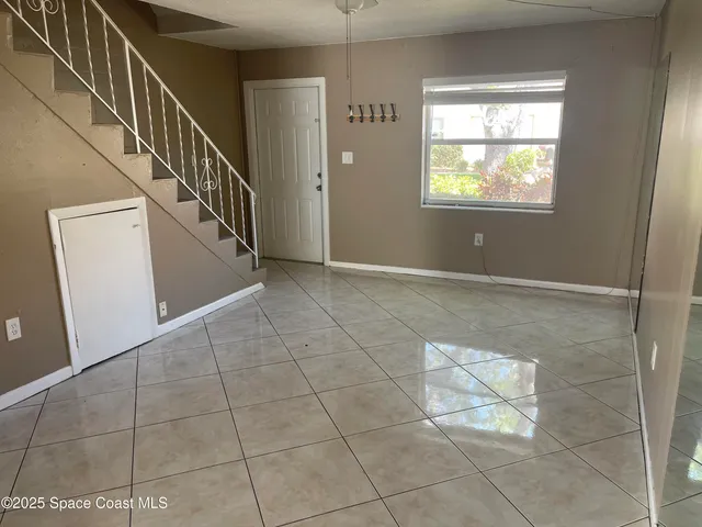 a view of an empty room with stairs and a window