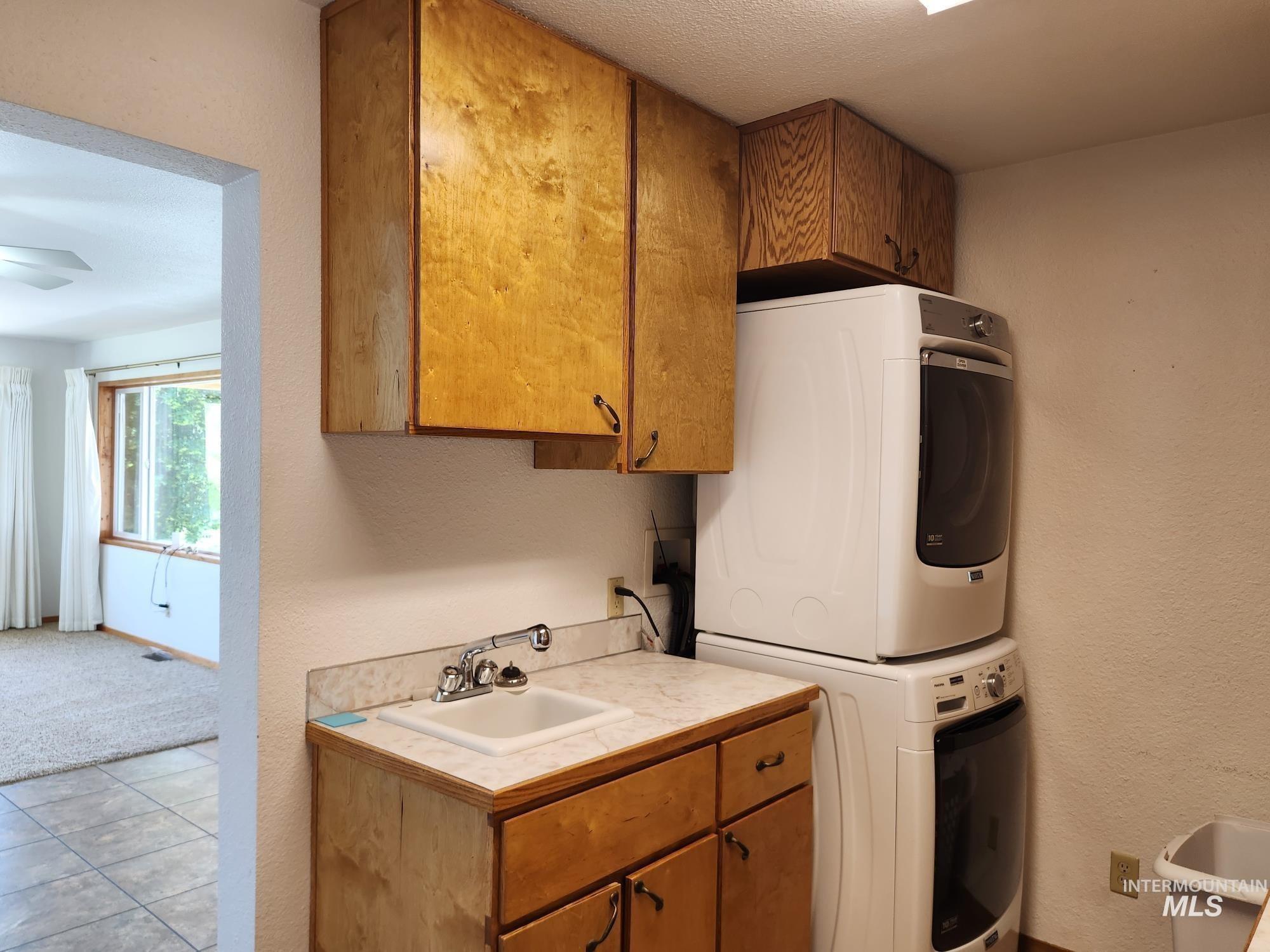 367 Woodland Road Kamiah, ID 83536 - Photo 12 of 49 Laundry room with a textured wall, stacked washer / drying machine, cabinet space, and a textured ceiling