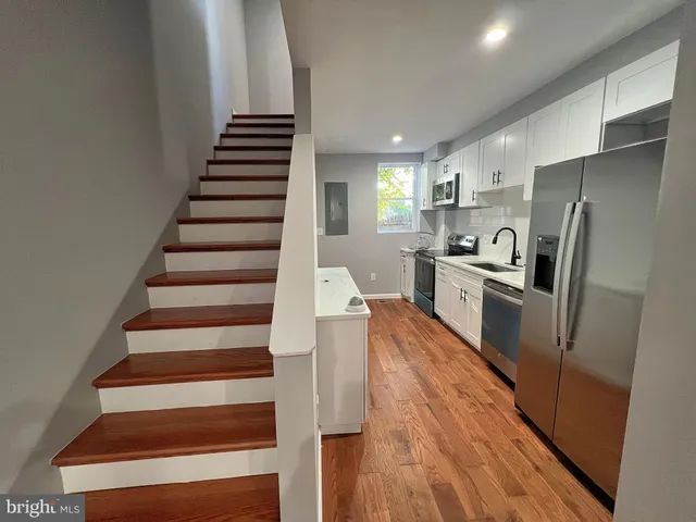 a kitchen with sink a refrigerator and wooden floor