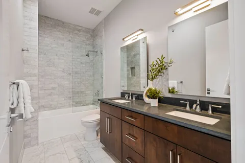 a bathroom with a granite countertop sink mirror and a bathtub