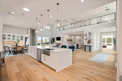 a large white kitchen with lots of counter space and chandelier